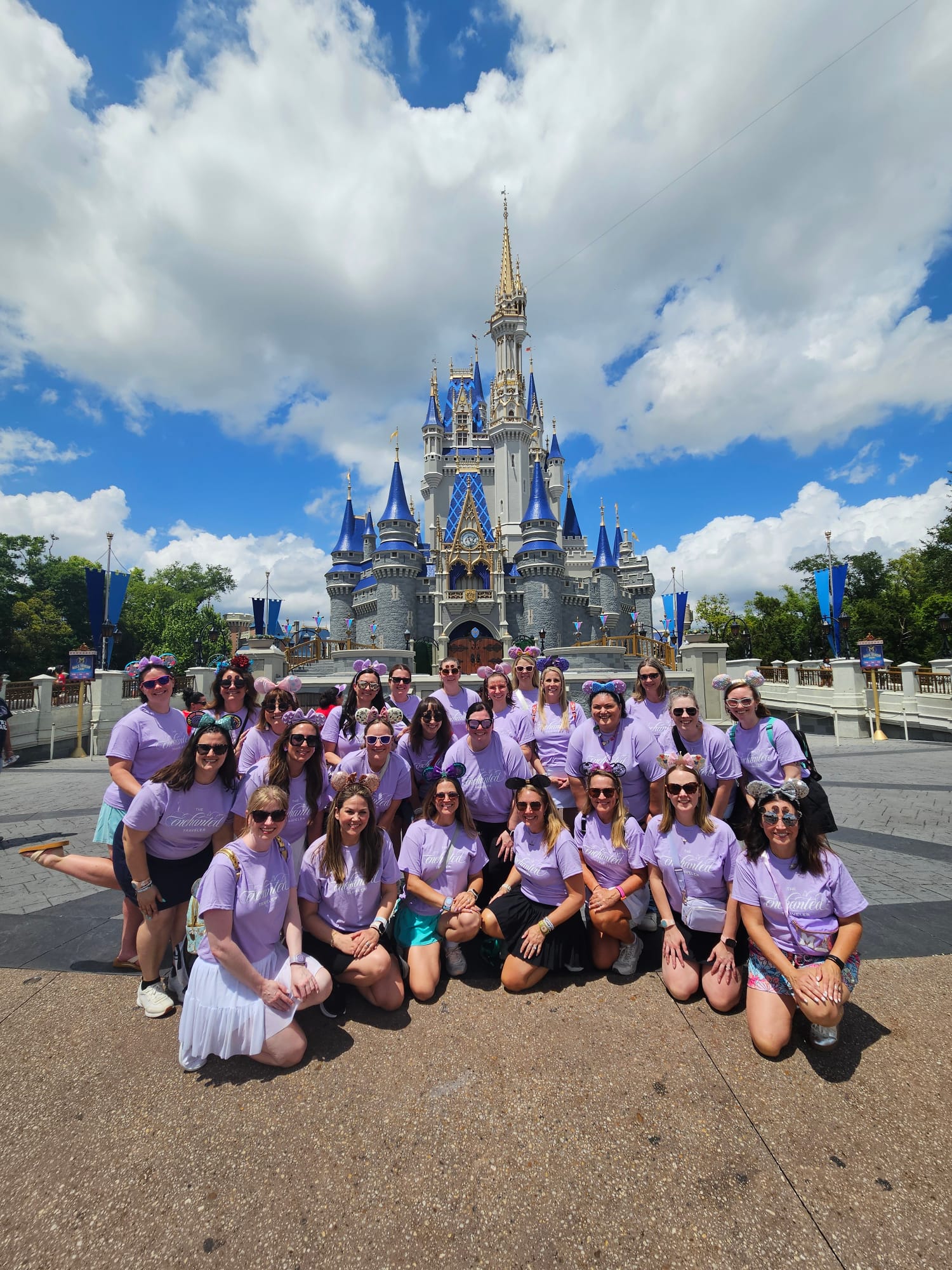 The Enchanted Traveler Disney travel agent team in matching lilac shirts in front of Cinderella Castle at Walt Disney World
