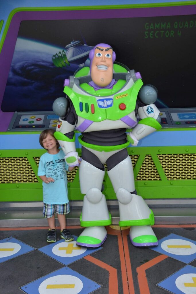 Young boy smiling next to Buzz Lightyear in Tomorrowland at Magic Kingdom